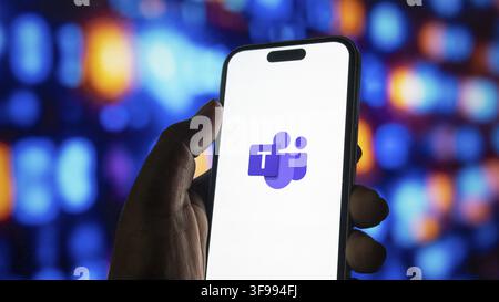 Person showing microsoft teams symbol on mobile phone, digital workplace tool for teamwork, video conferencing application, remote employment technolo Stock Photo