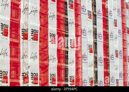 Detail of building wrapped in huge red and white Baumit branded banners as on site advertisement Stock Photo