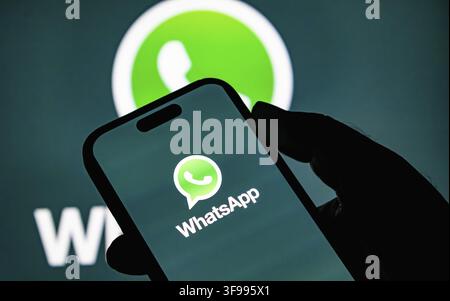 WhatsApp logo on smartphone screen. Social media communication platform. Tech device in silhouette. Digital connectivity concept. Global chat service Stock Photo