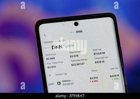 Smartphone displaying stock information for Denison Mines Corp against a blurred blue background Stock Photo