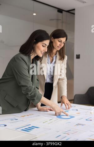 Experienced female analyst training colleague on data visualization at workplace Stock Photo