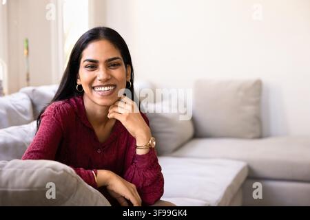 Portrait of beautiful Indian woman sitting comfortable on cozy sofa Stock Photo