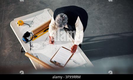 Blueprint, architecture and drawing with above of woman for building, construction site and renovation. Remodeling project, progress report and floor Stock Photo