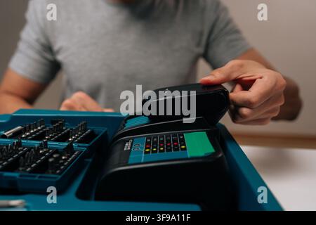 Close-up cropped shot of worker preparing tools, charging power drill battery for upcoming diy project, demonstrating home improvement and maintenance Stock Photo