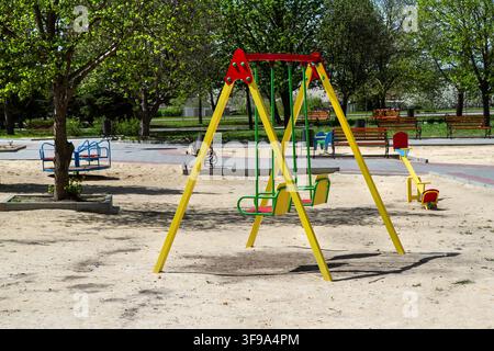 Colorful swing set on a playground in a public park. Empty outdoor recreation area for children. Stock Photo