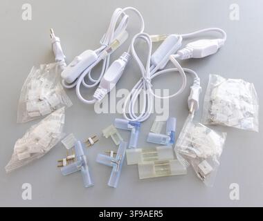 A collection of white LED strip light connectors and accessories on a grey surface Stock Photo