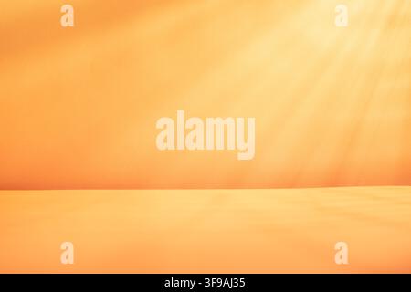 Bright orange background with soft light rays and empty tabletop for autumn product mockup festive banner or seasonal display Stock Photo