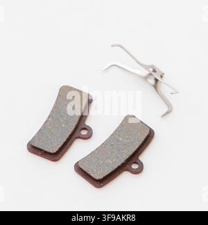Two new bicycle disc brake pads and a spring clip are shown Stock Photo