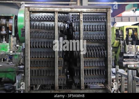 The image captures the interior of an industrial workshop, where a large number of metal tool semi-finished products are densely stacked in layers on Stock Photo