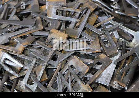 A large number of small metal parts with cutting and stamping traces and oxidized color on the surface are randomly stacked, showing the state of indu Stock Photo
