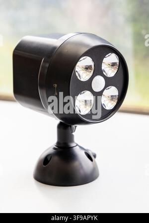 A black LED motion sensor security light sits on a white surface Stock Photo