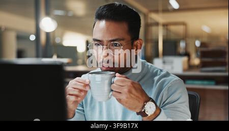 Computer, office and businessman with coffee at night with finance report, deadline and audit. Glasses, reading and person with caffeine drink for Stock Photo