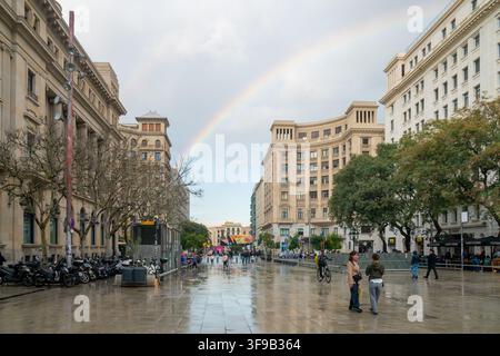 Barcelona, Spain - 11 march, 2025: A vibrant rainbow arches over a European city street after a rain shower, reflecting on the wet pavement and illumi Stock Photo