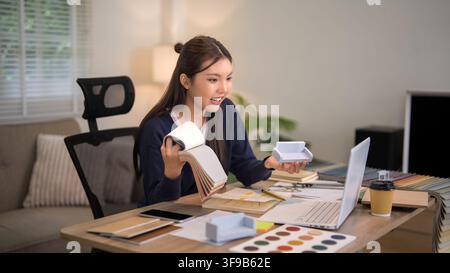 Female designer examining wood samples and paint colors for furniture project in bright contemporary workspace Stock Photo