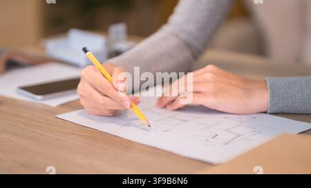 Hands of professional drawing architectural sketch on desk with notebook and warm beverage in creative studio setting Stock Photo