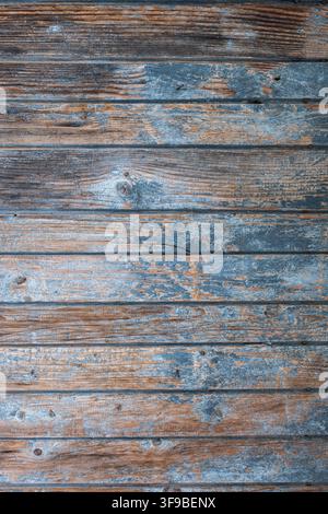 Close-up detail of an old wooden door made from horizontally oriented boards, featuring faded pastel blue paint, exposed wood and rusty nails. The age Stock Photo