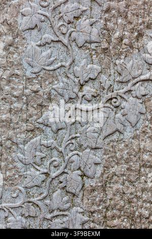 Detail of a carved stone relief depicting an ivy leaf and vine pattern on a weathered wall Stock Photo