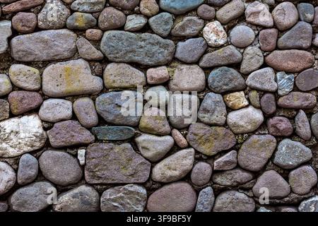 Traditional wall built from rounded river stones and pebbles set in mortar, rustic alpine texture Stock Photo