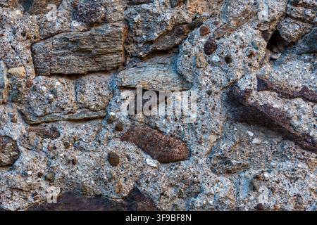 Rustic natural stone wall texture with rough aggregate rock fragments and irregular weathered surface Stock Photo