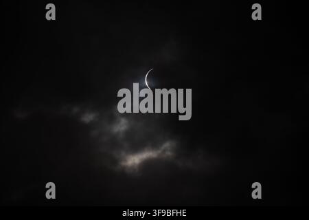 Iceland - 12 August 2026: View of a partial solar eclipse partially obscured by dark, moody clouds in the Westfjords Region. Stock Photo