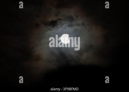 Iceland - 12 August 2026: View of a partial solar eclipse partially obscured by dark, dramatic clouds in the sky over the Westfjords Region. Stock Photo