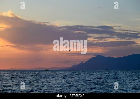 A tranquil seascape at twilight featuring a vast ocean expanse against the fading light, a prominent mountain range in the background Stock Photo