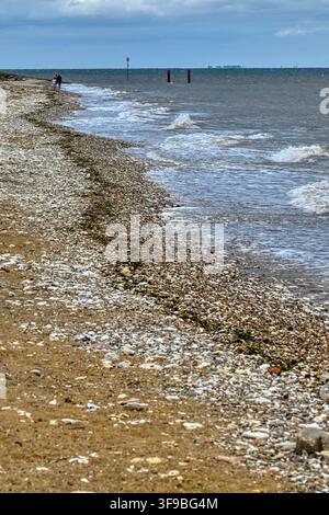 A distant family walk along Hunstanton South Beach at high tide on an overcast day Stock Photo