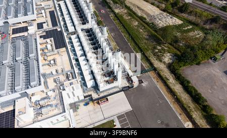 Aerial view of a modern hyperscale data center featuring rows of cooling units, server infrastructure, and solar panels, located in an industrial area Stock Photo