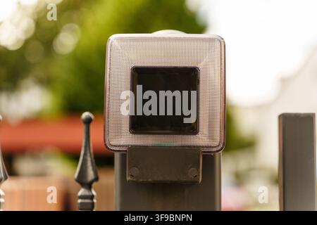 Solar powered square LED post cap light atop a black metal fence, ideal for residential outdoor security and energy efficient lighting Stock Photo