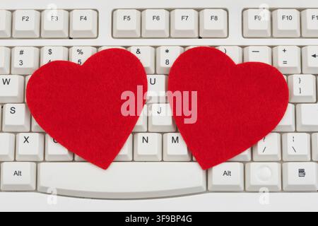 Blank red hearts on a white computer keyboard for online dating and workplace romances Stock Photo