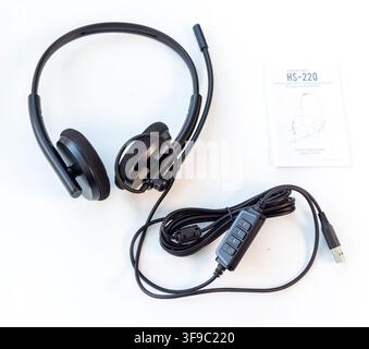A black USB headset with a manual is shown on a white background Stock Photo