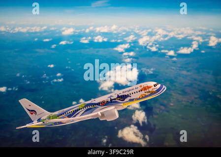 Chiang Mai, Thailand - 07 August 2026 : Bangkok Airways Samui whale shark livery model airplane flying above a green cloud dotted landscape Stock Photo