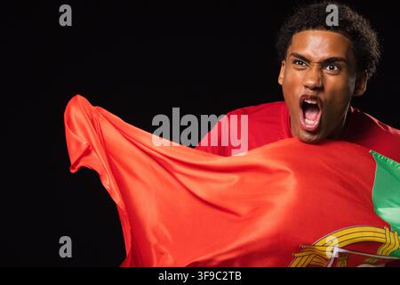 Man gripping flag, shouting, stretching red and green fabric in studio, red shirt, copy space Stock Photo