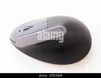 A black ergonomic wireless computer mouse rests on a white background Stock Photo