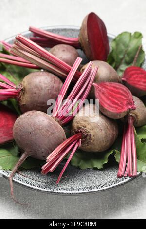 Whole and cut young beets with green leaves on table, closeup Stock Photo