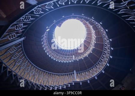 Spiral shape stairway in medieval stone tower . Black and white photograph of a bright circular skylight surrounded by hanging lights against a dark Stock Photo