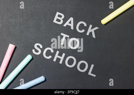 Back to school text written on a black chalkboard surrounded by colorful chalk sticks for education concept. High Quality Photo Stock Photo