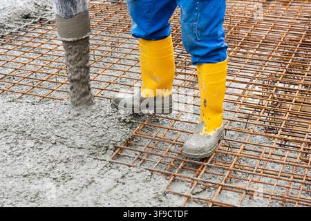 Betonieren von einem Fundament Bauarbeiter betonieren auf Baustahl ein Fundament für ein neues Wohnhaus als Symbolbild für Wohnungsbau und Bekämpfung der Wohnungsnot - FOTOMONTAGE - NUR FÜR REDAKTIONELLE VERWENDUNG - *** Pouring a Foundation: Construction workers are pouring concrete onto rebar to build a foundation for a new residential building, as a symbolic image of housing construction and the fight against the housing shortage. PHOTO MONTAGE FOR EDITORIAL USE ONLY Stock Photo