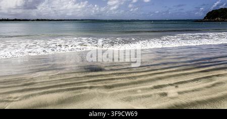 Rolling waves breaking onto a sandy tropical beach Stock Photo