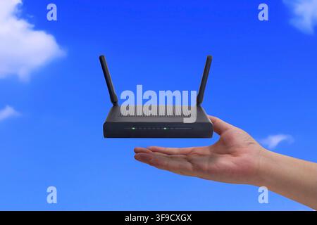 Conceptual image of a human hand holding a black wireless router with antennas. Global internet connection, cloud network technology, and high-speed W Stock Photo