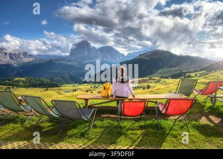 Woman hiker sitting on wooden bench looking at mountain view Stock Photo