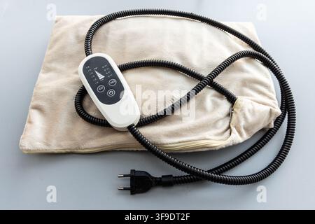 A fluffy beige electric heating pad with a digital controller is shown Stock Photo