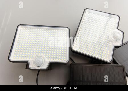 Two LED solar lights with motion sensors are shown on a grey background Stock Photo