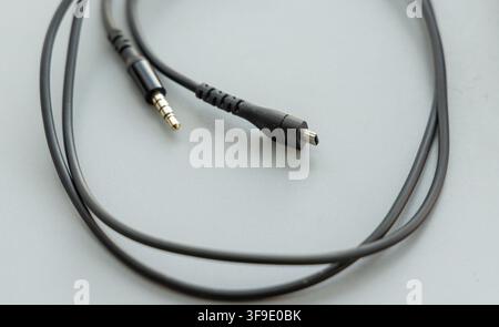 A black audio cable rests on a light gray background Stock Photo