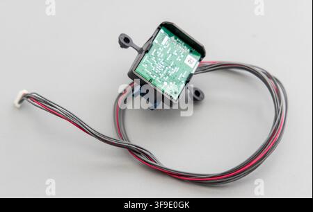 A small electronic circuit board with wires and connector lies on gray Stock Photo