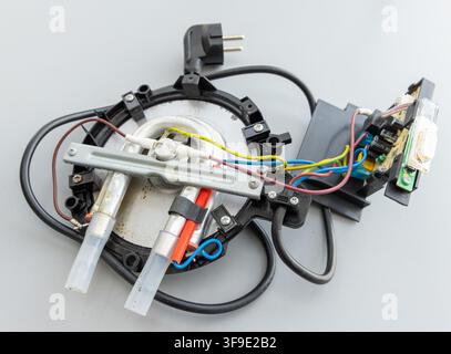 Internal components of a disassembled electric kettle are shown on a grey background Stock Photo