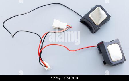 Two small internal laptop speakers with connecting wires on grey background Stock Photo