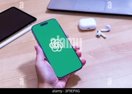 Hand holding an iPhone with the Open AI app logo. Stock Photo