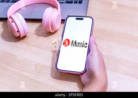 Hand holding an iPhone with the Youtube Music app logo. Stock Photo