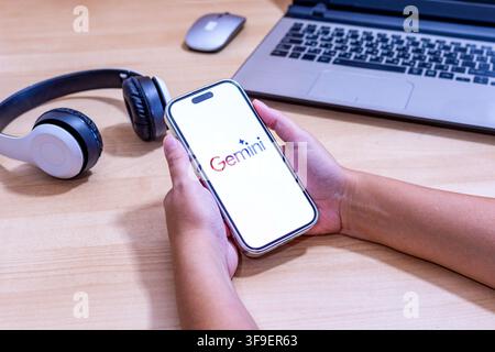 Hand holding an iPhone with the Gemini AI app logo. Stock Photo